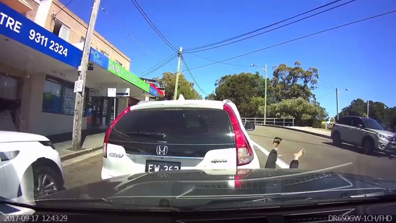 Idiot Road-Blocker Exits His Car While In Reverse, Gets Knocked Over, Blames Another Driver