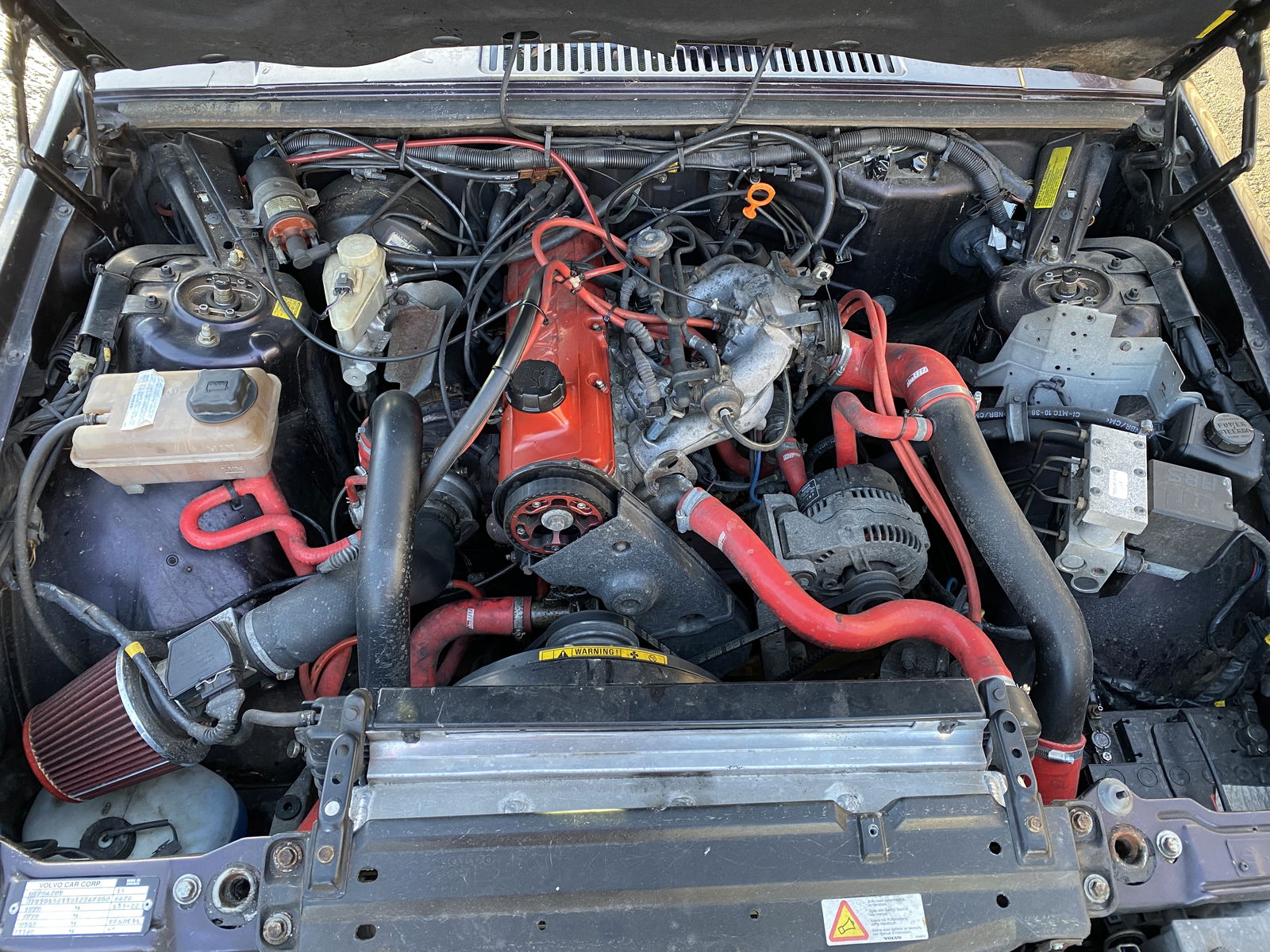 The engine bay looking decidedly more red. The aircon had to be deleted to make room, good job the windows work.